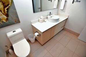 Une salle de bain moderne avec des toilettes, un lavabo et un miroir.