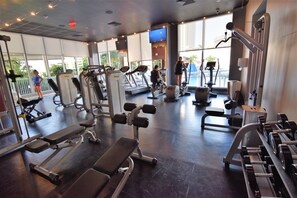 Une salle de sport équipée de divers appareils d’exercice, dotée de grandes fenêtres et offrant une vue sur l’extérieur.