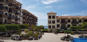 Ein Resort mit mehrstöckigen Gebäuden, einem Schwimmbad und angelegten Grünflächen mit Steinen und Bäumen.