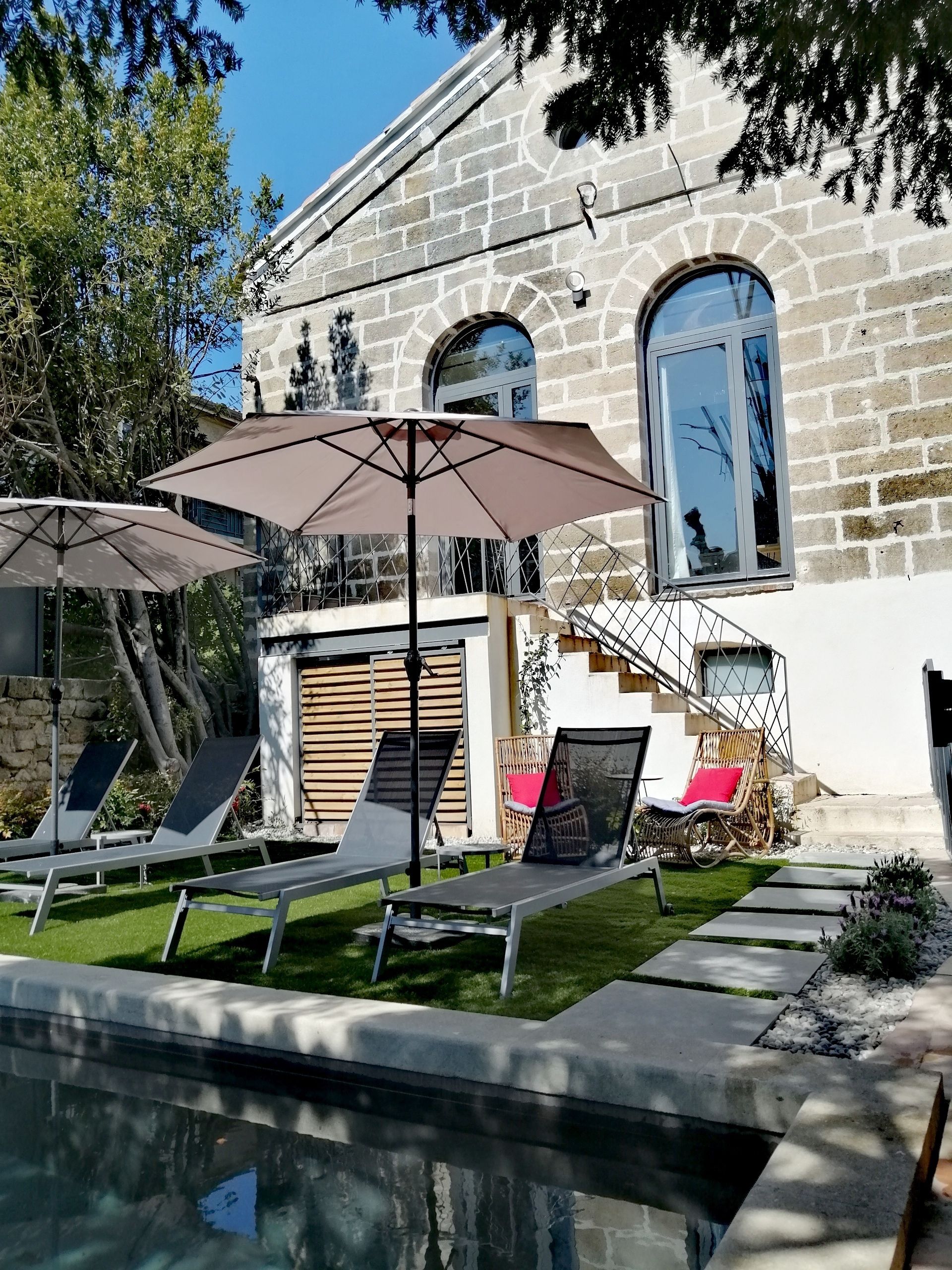 Ein Steinhäuschen mit Swimmingpool, Sitzgelegenheiten im Freien und einer Treppe, die zu einem Balkon führt.