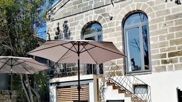 Ein Steinhäuschen mit Swimmingpool, Sitzgelegenheiten im Freien und einer Treppe, die zu einem Balkon führt.