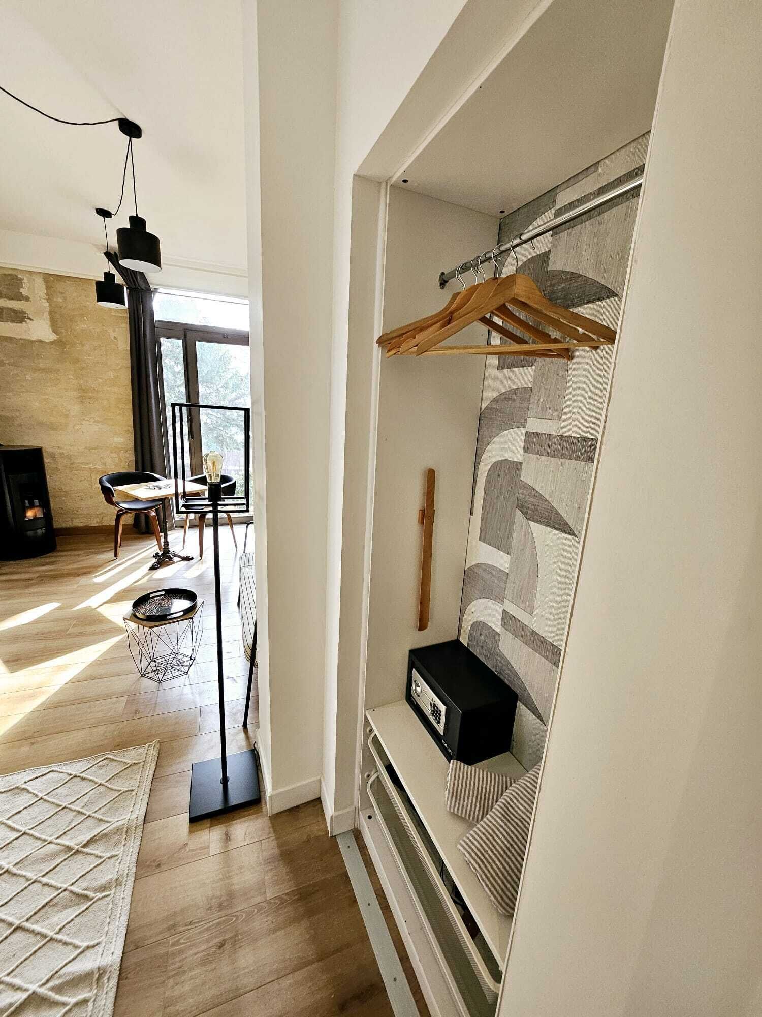 Een moderne woonkamer met een houten vloer, een zwarte bank, een salontafel en een hanglamp.