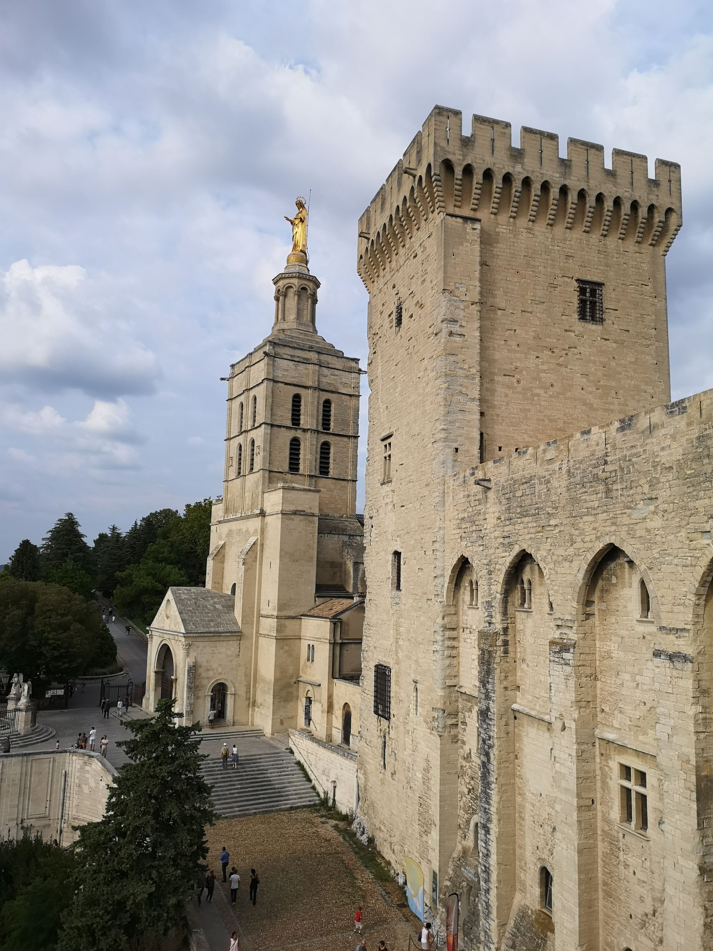 A historic stone building with a prominent tower and a statue on top.