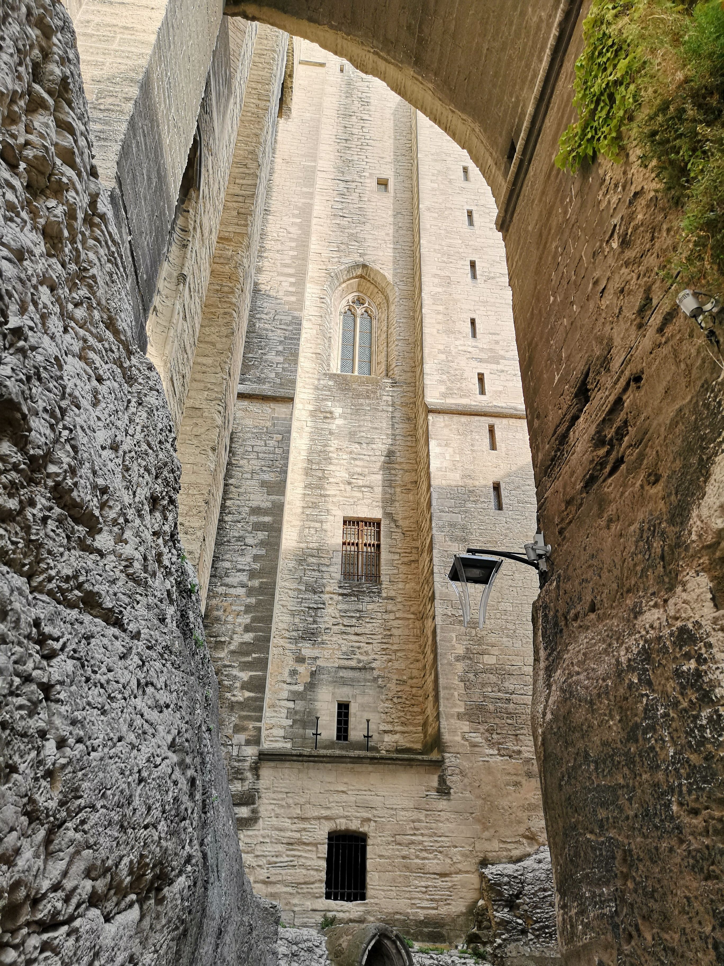 Un edificio de piedra con un gran arco de entrada, un estrecho pasaje y una pequeña ventana con celosía.