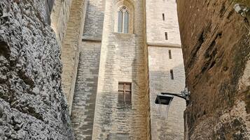 Un edificio de piedra con un gran arco de entrada, un estrecho pasaje y una pequeña ventana con celosía.