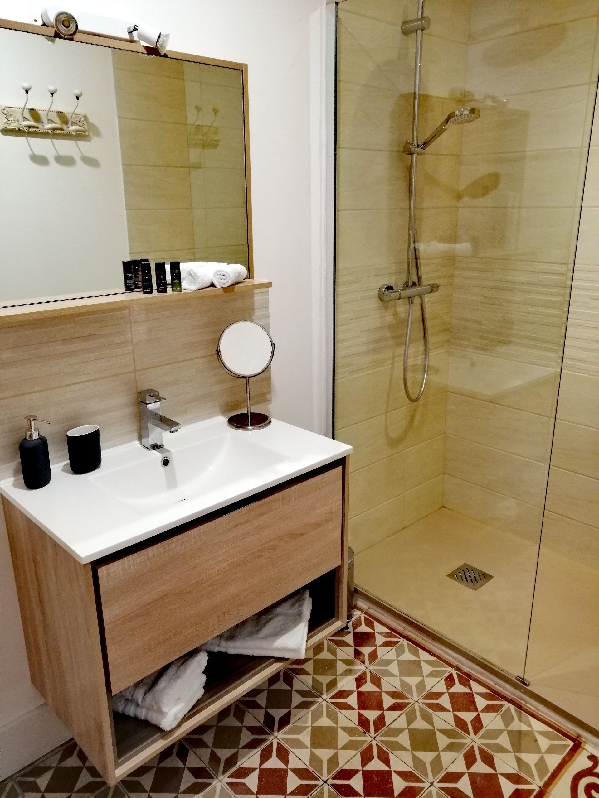 Un baño moderno con lavamanos blanco, espejo y cabina de ducha de vidrio.