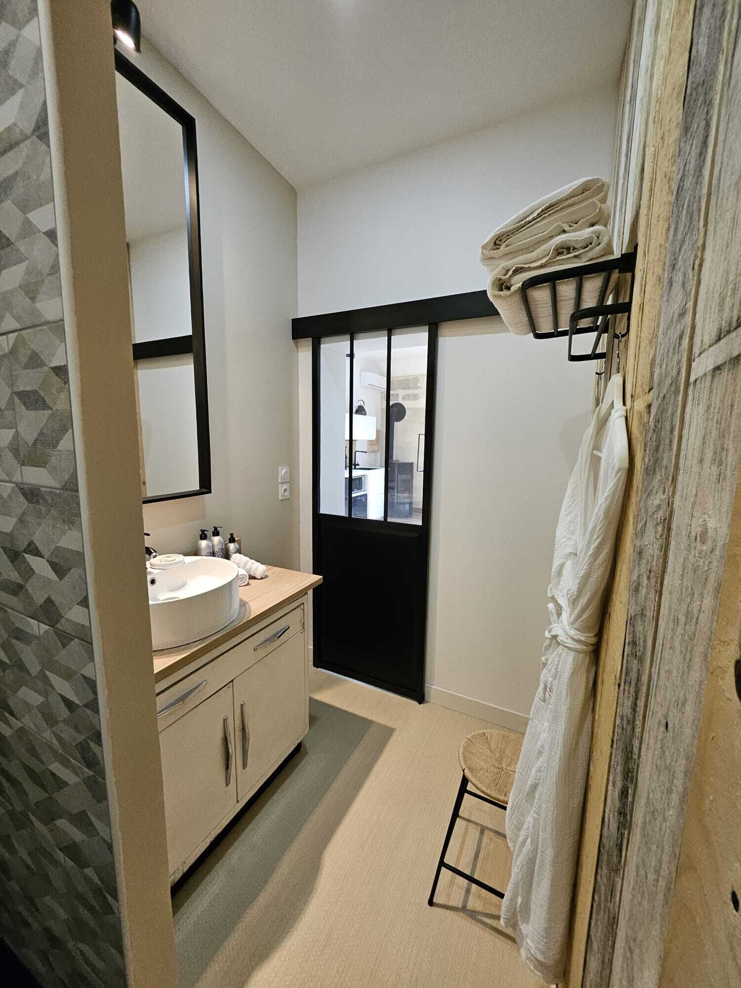 Een moderne badkamer met een grote spiegel, een wastafel en een raam.