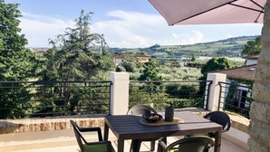 An outdoor patio with a table and chairs, a view of a rural landscape, and a pergola providing shade. - Linda apartment, 300 meters from the sea in a typical cottage perfect for families (Martinsicuro)