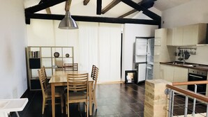 A dining area with a wooden table and chairs, a bookshelf, and a kitchen area with appliances. - Linda apartment, 300 meters from the sea in a typical cottage perfect for families (Martinsicuro)