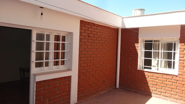A building with a red brick exterior, white window frames, and a flat roof. - Accommodation Tierras del sol (Entire House 2 bedrooms, close to the Center) (Las Heras)