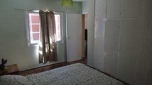 A bedroom with a bed, a wardrobe, a window with curtains, and a hanging light fixture. - Accommodation Tierras del sol (Entire House 2 bedrooms, close to the Center) (Las Heras)