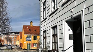 En byggnad med en vit fasad, en tydligt markerad entré och en cykel parkerad utanför.