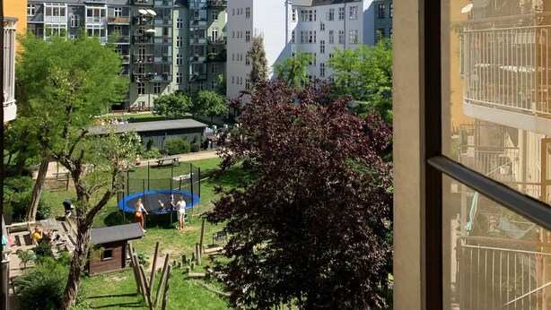 Ett bostadsområde med flerfamiljshus, en lekplats och en klar, blå himmel.