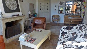 Un salon chaleureux avec une cheminée, un fauteuil en cuir et une table basse sur laquelle sont posés des magazines.