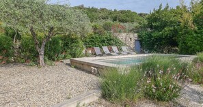 A pool area with a stone wall, lounge chairs, and surrounding greenery. - Provençal farmhouse with pool in the Drôme Provençale, La Garde-Adhémar (La Garde-Adhémar)