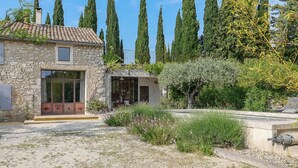 Une maison en pierre avec un toit en tuiles, une grande fenêtre et un petit porche.