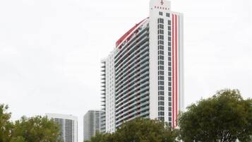 A tall, modern hotel building with a red and white color scheme, featuring multiple balconies and a prominent signage at the top.