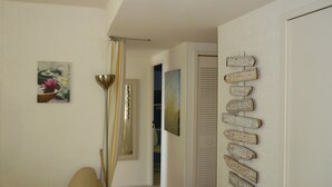 A hallway with a beige sofa, a mirror, a lamp, and a wall with directional signs. - 800m from the sea, pretty Provencal villa, quiet, swimming pool, garden in the Golf St. Tropez (Roquebrune-Sur-Argens)