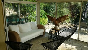A sunlit patio with a white sofa, two black chairs, and a decorative bird sculpture. - 800m from the sea, pretty Provencal villa, quiet, swimming pool, garden in the Golf St. Tropez (Roquebrune-Sur-Argens)