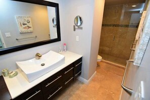 A bathroom with a white sink, dark wooden cabinets, a large mirror, and a glass shower enclosure. - Beautiful 2 Bedroom + 2 Baths On The Ocean At Sian (Hollywood)