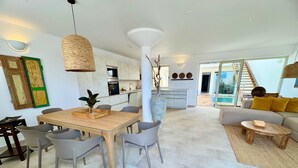 A modern living room with a sofa, coffee table, and dining area with chairs and a wooden table. - Bungalow with private pool, internet, close to the sea, courtyard, top location, parking lot (Costa Calma)