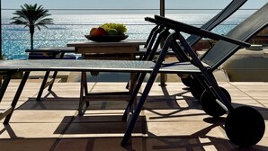 A balcony with a table, a bowl of fruit, and two lounge chairs facing the sea. - Bungalow with private pool, internet, close to the sea, courtyard, top location, parking lot (Costa Calma)