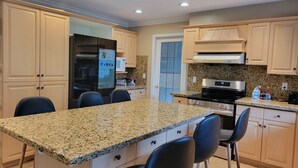 A kitchen with granite countertops, a stainless steel refrigerator, and a built-in oven. - Family home in Surrey (Surrey)