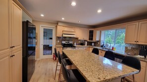 A modern kitchen with granite countertops, stainless steel appliances, and a large island with bar stools.