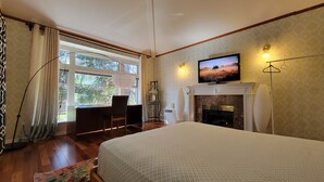 A bedroom with a bed, a desk, a chair, a fireplace, a TV, and a window with curtains. - Family home in Surrey (Surrey)