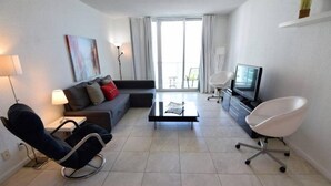 A modern living room with a sofa, a recliner, a coffee table, a TV, and a chair. - Incredible 2 Bed 2 Bath On The Beach @Tides (Hollywood)