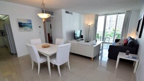 A modern living room with a dining area, a sofa, a TV, and a balcony with a view. - Tides-5q (Hollywood)