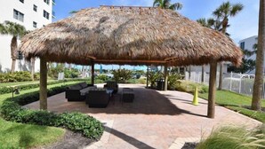 A thatched-roof outdoor seating area with a pool in the background. - Tides-5q (Hollywood)