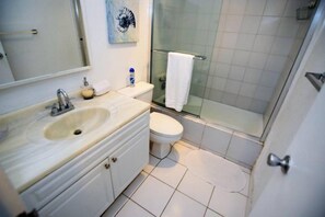 A bathroom with a sink, toilet, and glass shower enclosure. - Tides-5q (Hollywood)