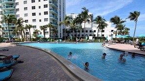 A swimming pool surrounded by palm trees and a multi-story building with balconies. - Tides-5q (Hollywood)