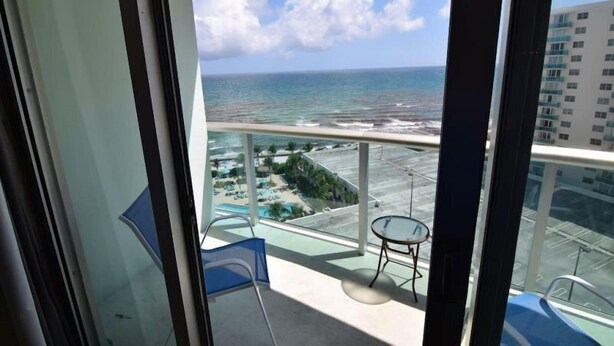 Ein Balkon mit Blick auf das Meer und einen Poolbereich.