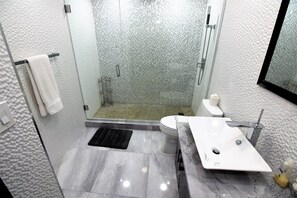 A modern bathroom with a glass-enclosed shower, a white toilet, and a marble sink.