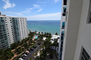 A high-rise hotel with a view of the ocean and a pool area.