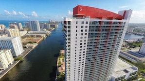 Un edificio alto con un techo rojo característico, un río a su lado y otros edificios cercanos.