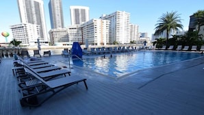 Una piscina en la azotea con sillones de descanso y vista panorámica de la ciudad.