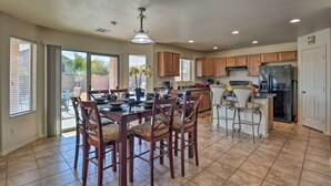 A spacious kitchen with wooden cabinets, a central island with bar stools, and a large dining table with chairs. - Relaxing San Tan Valley Retreat w/ Pool & Hot Tub! (San Tan Valley)