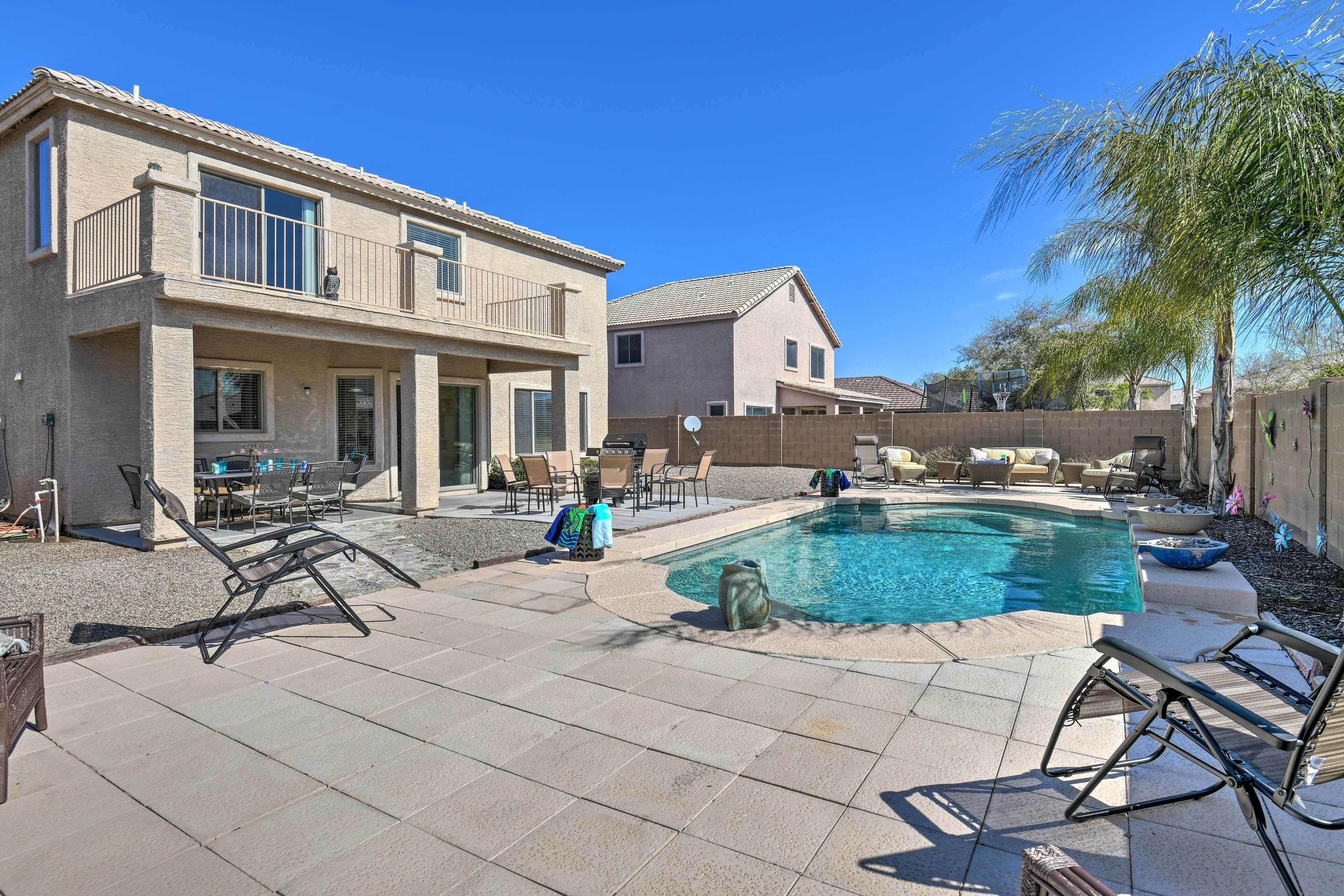 A residential property with a swimming pool, outdoor seating, and a patio area.