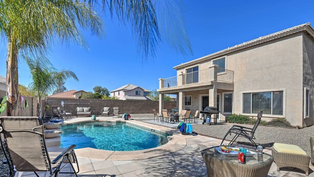 A swimming pool with lounge chairs and a table, surrounded by a house and palm trees. - Relaxing San Tan Valley Retreat w/ Pool & Hot Tub! (San Tan Valley)