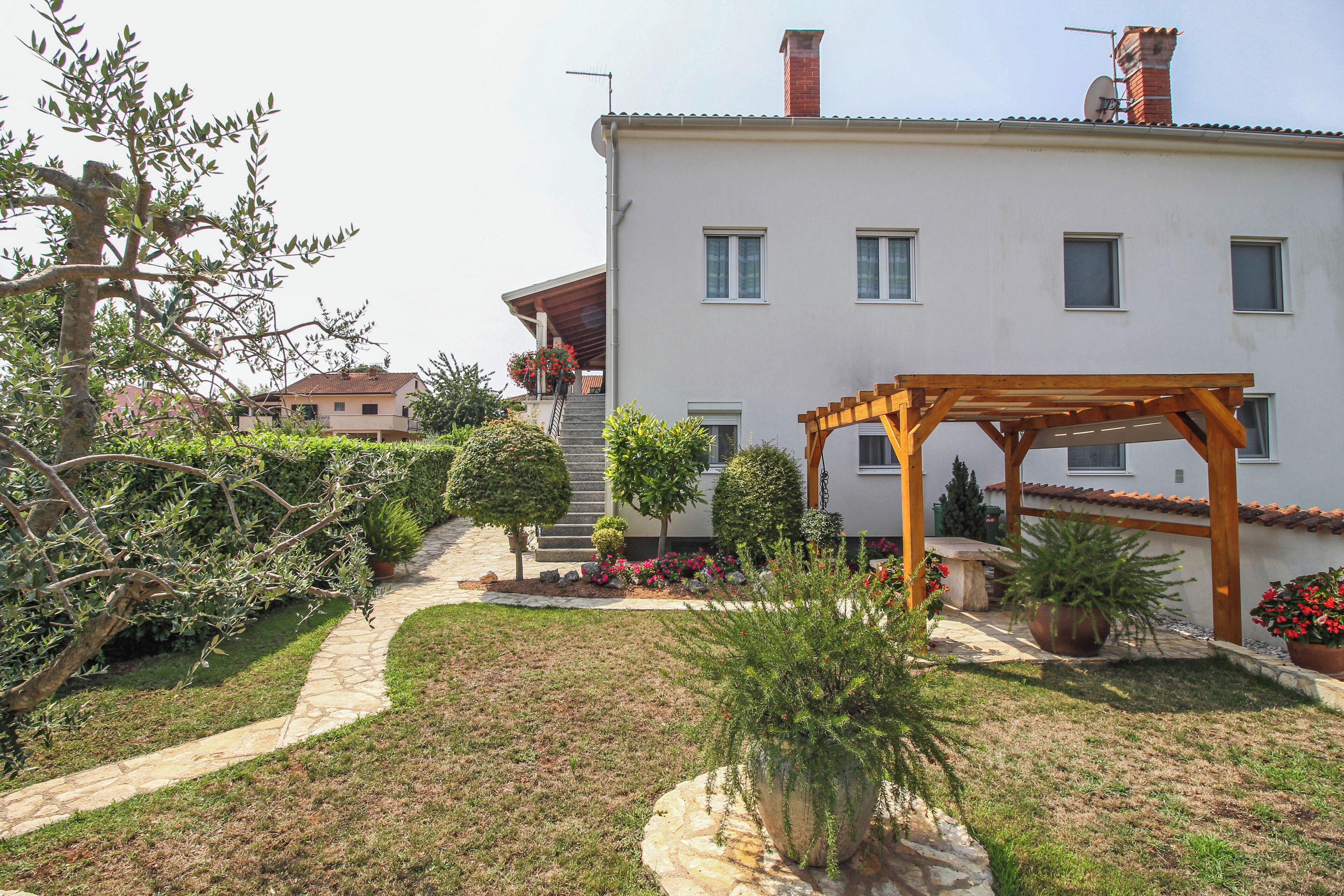 A two-story building with a covered patio, a stone pathway, and well-maintained landscaping.