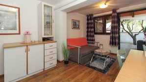 A compact living space with a kitchenette, a sofa, a dining area, and a window with curtains.