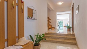 Un espace d’accueil avec un bureau en bois, un panier en osier contenant une plante et un tableau blanc fixé au mur.
