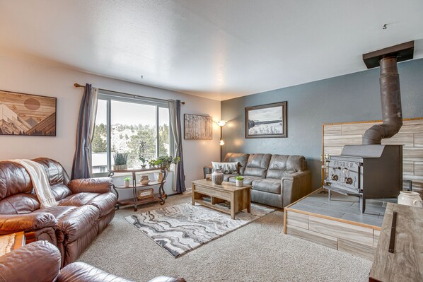 A cozy living room with leather sofas, a fireplace, and a view of the outdoors.
