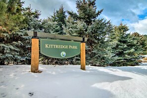 A sign for Kittredge Park surrounded by snow-covered trees.