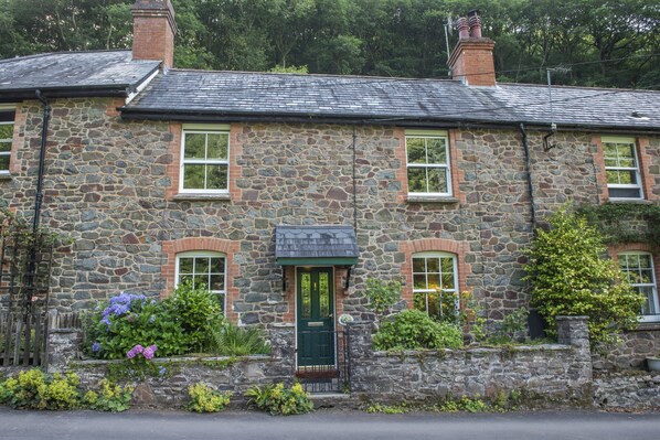 A stone building with a green door, windows, and a chimney. - Robins Brook, Porlock (Porlock)
