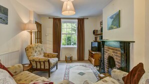 A cozy living room with a fireplace, a comfortable armchair, a sofa, and a small table. - Robins Brook, Porlock (Porlock)