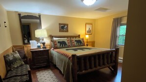 Un dormitorio con una cama de madera, una mesita de noche, una lámpara, un espejo, una silla y una ventana con cortinas.